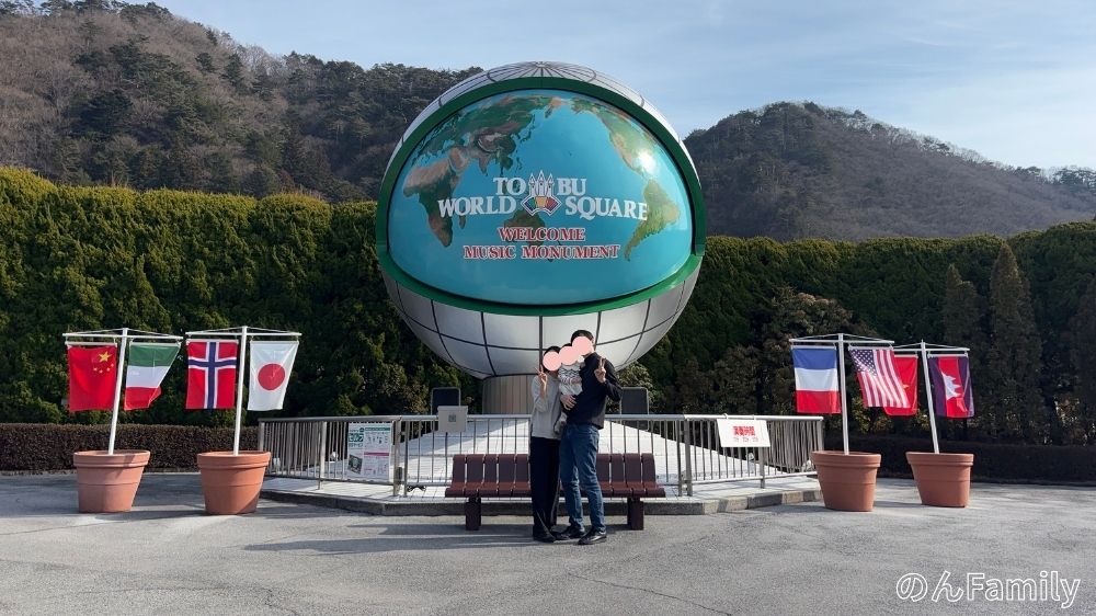日光の東武ワールドスクウェア入り口にある地球儀のモニュメント前で、11ヶ月の赤ちゃんと家族で記念撮影をする様子
