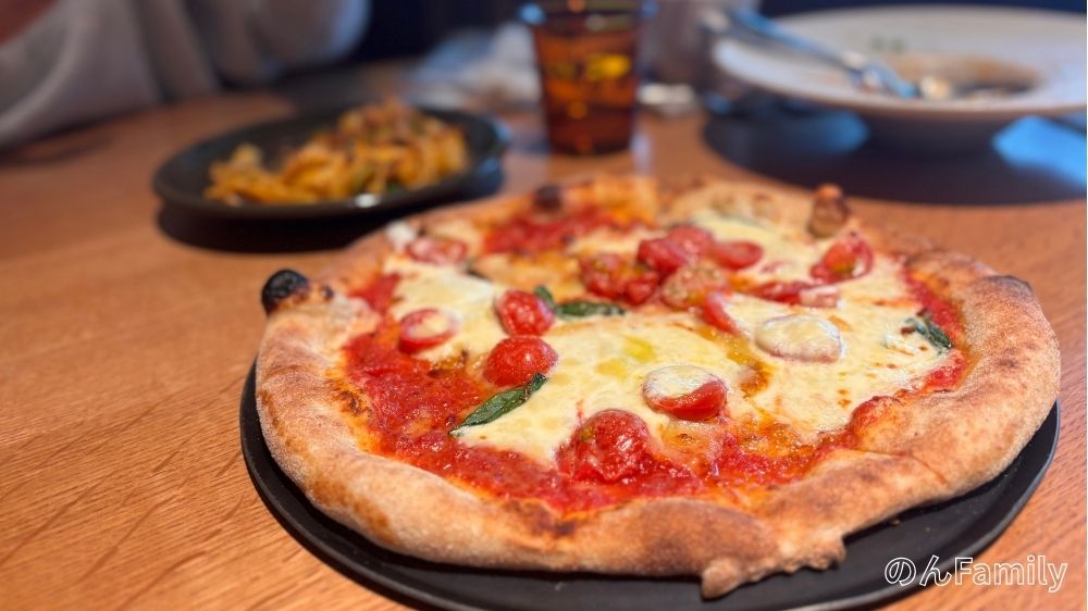 GARDEN HOUSE TAKANAWAで提供される焼きたてのマルゲリータピザとパスタ。木目調のテーブルに並ぶ本格的なイタリアンランチの様子。