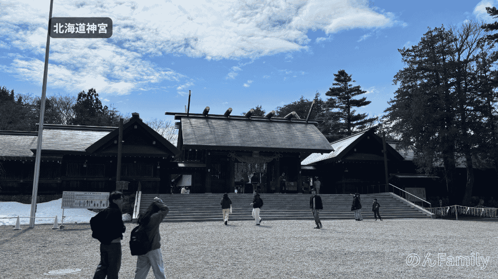 3月末の北海道神宮の神門前。手前に広がる一面の砂利道と階段、参拝客が歩いている様子、左側に少し残雪がある風景