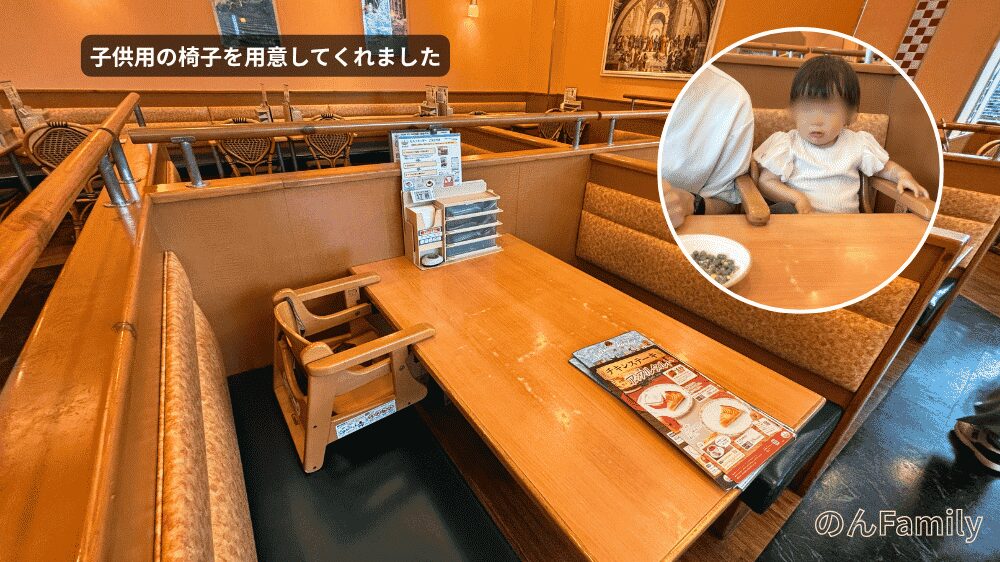 サイゼリヤ有明フロンティアビル店のボックス席（ソファ席）に設置された、ベルト付きの木製子ども用椅子の写真。ワイプには、実際にその椅子に座ってパパの隣でランチを待つ1歳児の娘の様子が写っている。